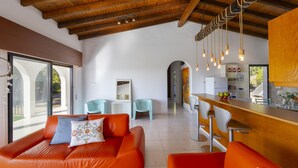 Een modern interieur met een houten plafond, oranje banken, een keukenhoek en een eethoek.
