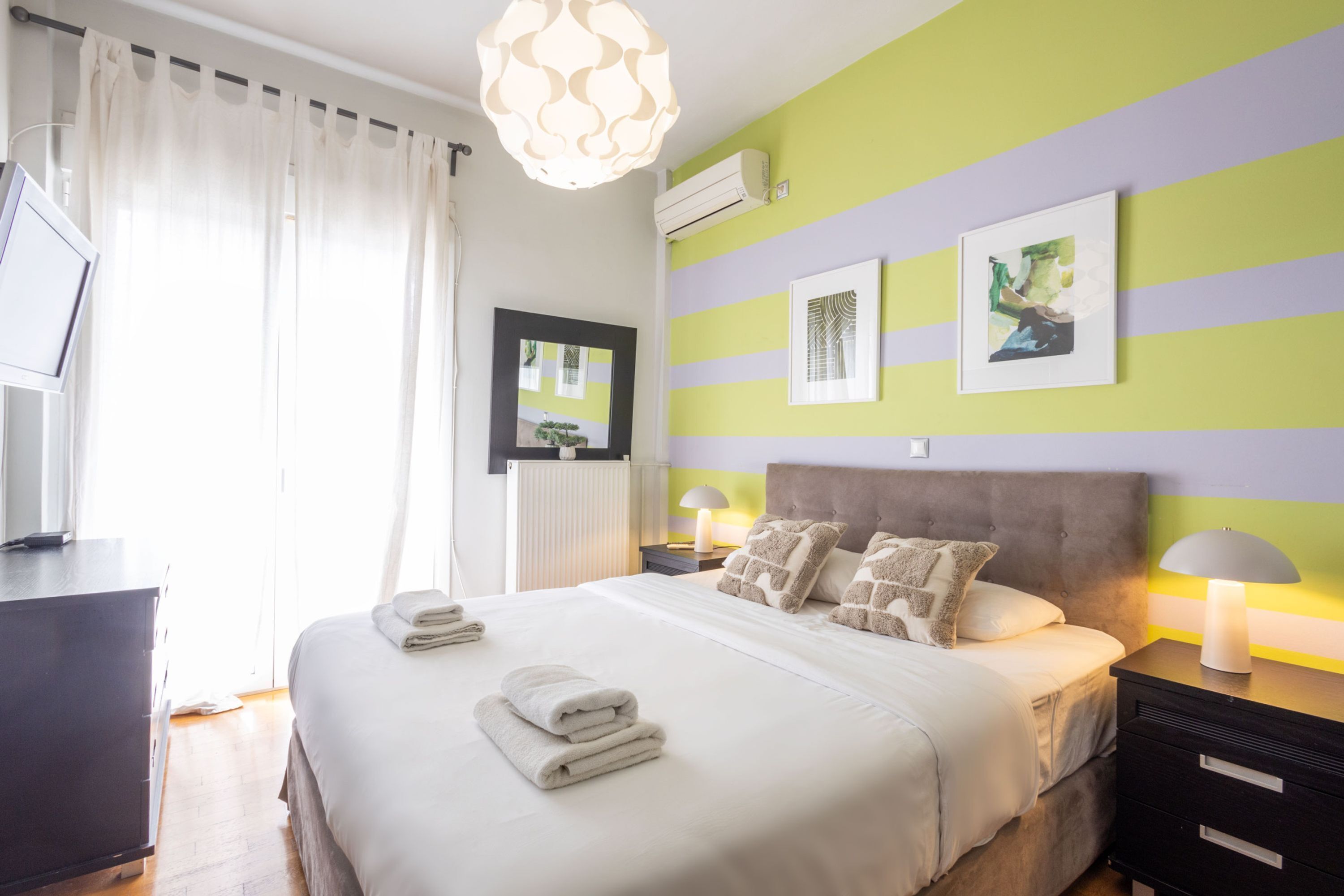 A neatly made bed with folded towels, a bedside lamp, and a framed picture on the wall.