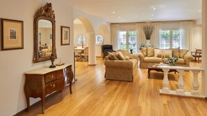 Un salon spacieux doté d’un parquet, d’un grand miroir décoratif et d’un ensemble de meubles de salon de couleur beige.