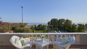 Un balcon avec des meubles en osier, une vue sur la mer et un lampadaire.