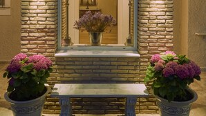 Une façade en pierre avec un banc et des plantes en pot devant.