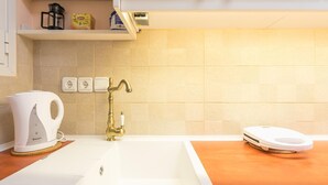 A modern kitchen with a white sink, a coffee maker, and a scale on the countertop. - Thissio Cocoon For Two (Athens)