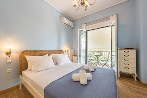 Et soveværelse med seng, et natbord, en kommode, en balkon med bord og stole samt en aircondition.