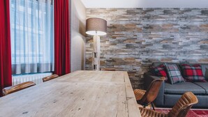 A dining area with a wooden table, chairs, a lamp, and a stone-patterned wall. - Alpine City Living - TOP 21 (Zell am See)