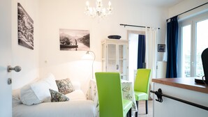 A room with a bed, two chairs, a table, a cabinet, a chandelier, and a window with curtains. - Living Eden - TOP 1 in Zell am See (Zell am See)