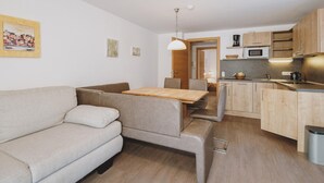 A compact living space with a sofa, a dining table, and a kitchenette. - Appartements Sulzer - TOP 11 (Zell am See)