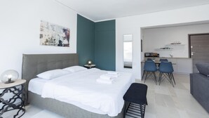 A modern hotel room with a large bed, a desk, and a kitchenette. - Hip And Fun in Athens Apt B (Athens)