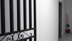 A hallway with a black and white striped gate, a door, and a mop leaning against the wall. - Hip And Fun in Athens Apt B (Athens)