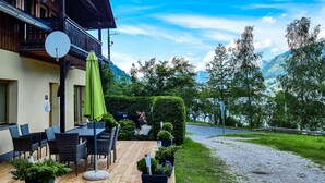 Eine Holzterrasse mit Gartenmöbeln, einer Satellitenschüssel und einem grünen Sonnenschirm.