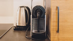 A kitchen with a coffee maker, kettle, and wooden cabinet. - Alpine City Living - TOP 31 (Zell am See)