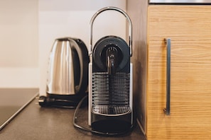 Ett kök med en kaffebryggare, vattenkokare och ett träskåp.