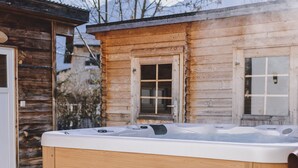 A wooden cabin with a hot tub, steps leading to the tub, and a door. - Chalet Molly in Zell am See (Zell am See)