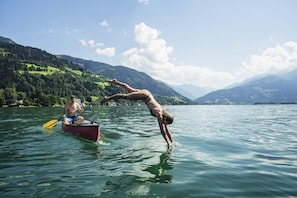 A person performing a handstand in a lake with mountains in the background. - Chalet Molly in Zell am See (Zell am See)