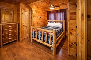 A wooden cabin room with a bed, a dresser, and a ceiling fan. - Private Large Mountaintop Cabin w/ wraparound deck (Dobson)
