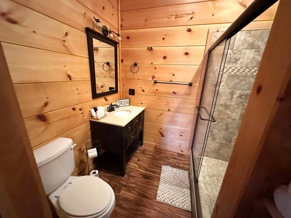 A wooden cabin bathroom with a toilet, sink, and mirror. - Private Large Mountaintop Cabin w/ wraparound deck (Dobson)