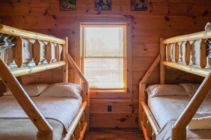 A cabin with two bunk beds, a window with blinds, and wooden walls. - Private Large Mountaintop Cabin w/ wraparound deck (Dobson)