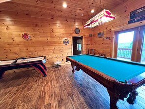 A pool table with a billiard cue and a pool table in a wooden room with a clock and a sign on the wall. - Private Large Mountaintop Cabin w/ wraparound deck (Dobson)