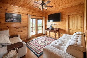 A wooden cabin interior with a sofa, a desk, and a television. - Private Large Mountaintop Cabin w/ wraparound deck (Dobson)