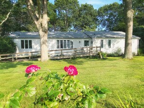 Een wit huis met een houten terras en een overdekte veranda.
