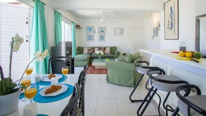 Eine moderne Küche mit Essbereich, grünen Möbeln und einer weißen Arbeitsplatte mit Früchten.