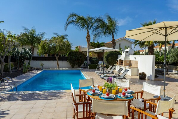 Relax by the clear pool surrounded by lush greenery and comfortable lounge chairs.