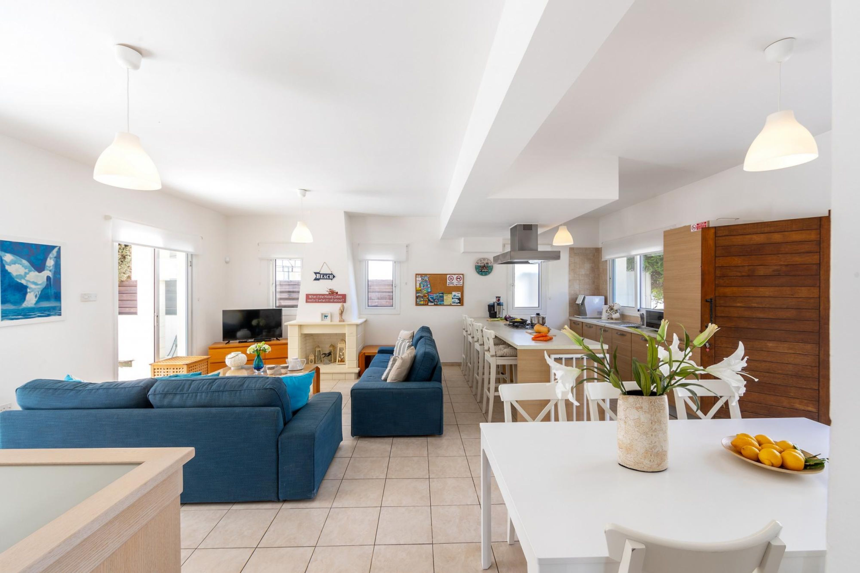 A modern living room with a sofa, dining table, and kitchen area.