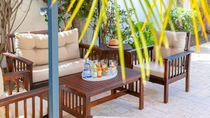 An outdoor seating area with wooden furniture and a table set with drinks and snacks. - Protaras Villa Athamas Blue (Paralimni)