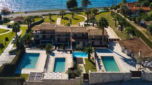 A large villa with multiple swimming pools, a well-maintained garden, and a view of the sea. - Palmrise Luxury Villas - Anemos Villa (Kassandra)