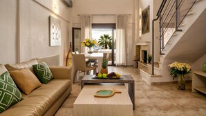 A spacious living room with a sofa, coffee table, and a staircase. - Palmrise Luxury Villas - Anemos Villa (Kassandra)