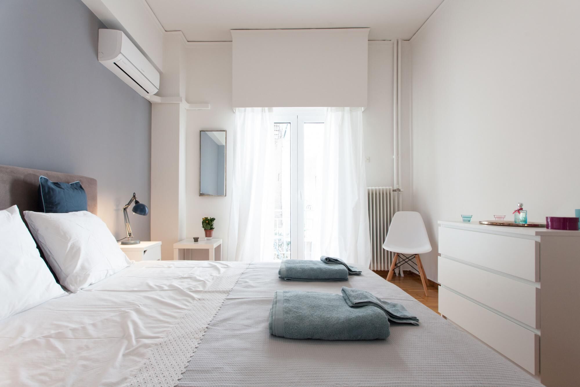 A modern bedroom with a large bed, bedside tables, a chair, and a dresser.