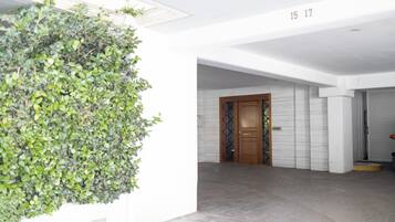 A hallway with a green wall, a wooden door, and a number '15 17' on the wall.