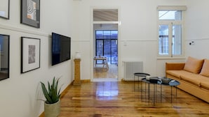 A modern living room with a wooden floor, a sofa, a TV, and framed artwork on the wall. - Incomparable Plaka s Lux 2bdrm Apt w Pvt Heated Pool (Athens)
