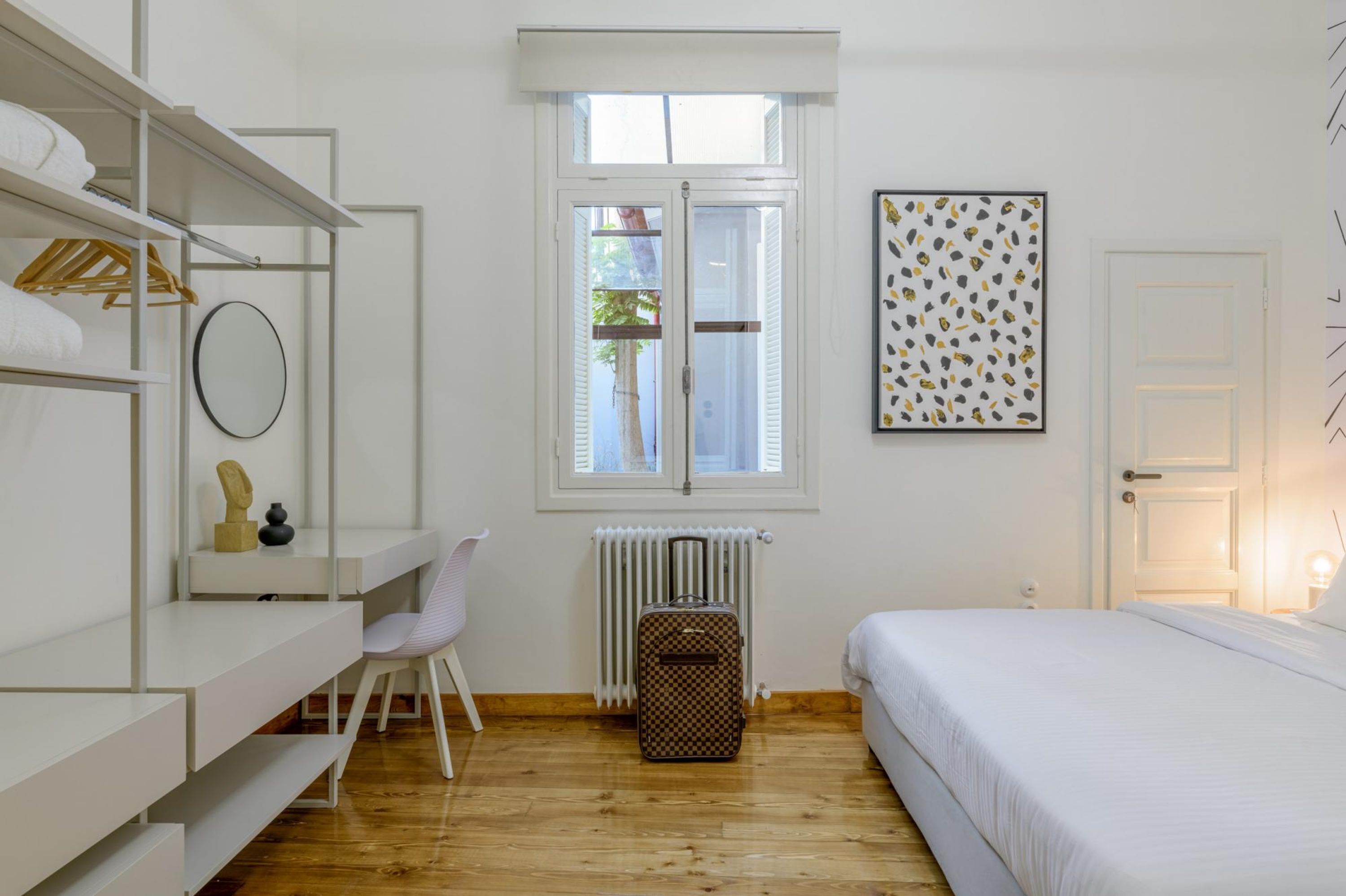 Une chambre à coucher avec un lit, un bureau et une chaise, un radiateur et une fenêtre.