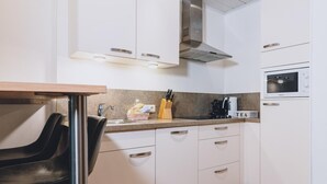 A modern kitchen with white cabinets, a stainless steel range hood, a built-in microwave, and a coffee maker. - Alpine City Living - TOP 32 (Zell am See)