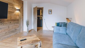 Una sala de estar con pared de madera, un sofá, una mesa de centro y un televisor.