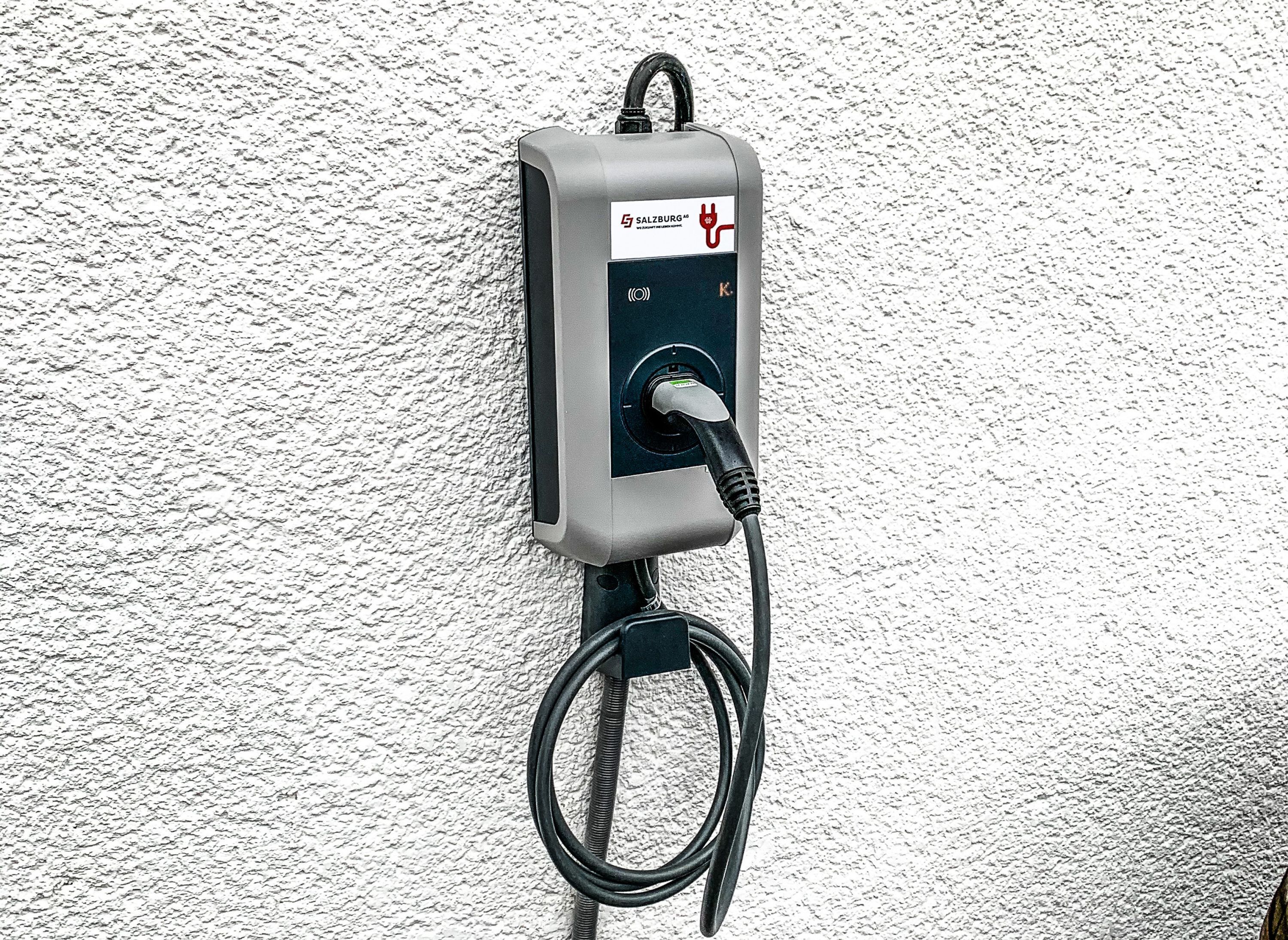 Una estación de carga para vehículos eléctricos instalada en la pared, con un cable conectado.