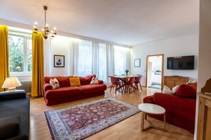 A living room with a red sofa, a dining table, and a TV. - Living Eden - TOP 2 in Zell am See (Zell am See)