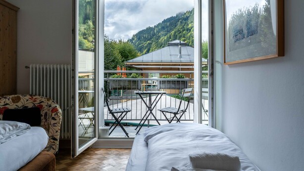 Une chambre avec un lit, une chaise et un balcon équipé d’une table et de chaises.