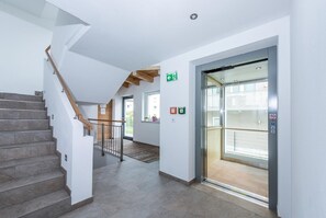 A modern interior with a staircase, an elevator, and a hallway. - Appartements Sulzer - TOP 13 (Zell am See)
