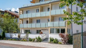 A multi-story building with balconies, a sign reading "APARTMENTS," and a well-maintained garden area. - Appartements Sulzer - TOP 13 (Zell am See)
