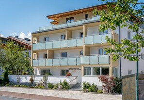 A multi-story building with balconies, a sign reading "APARTMENTS," and a well-maintained garden area. - Appartements Sulzer - TOP 13 (Zell am See)