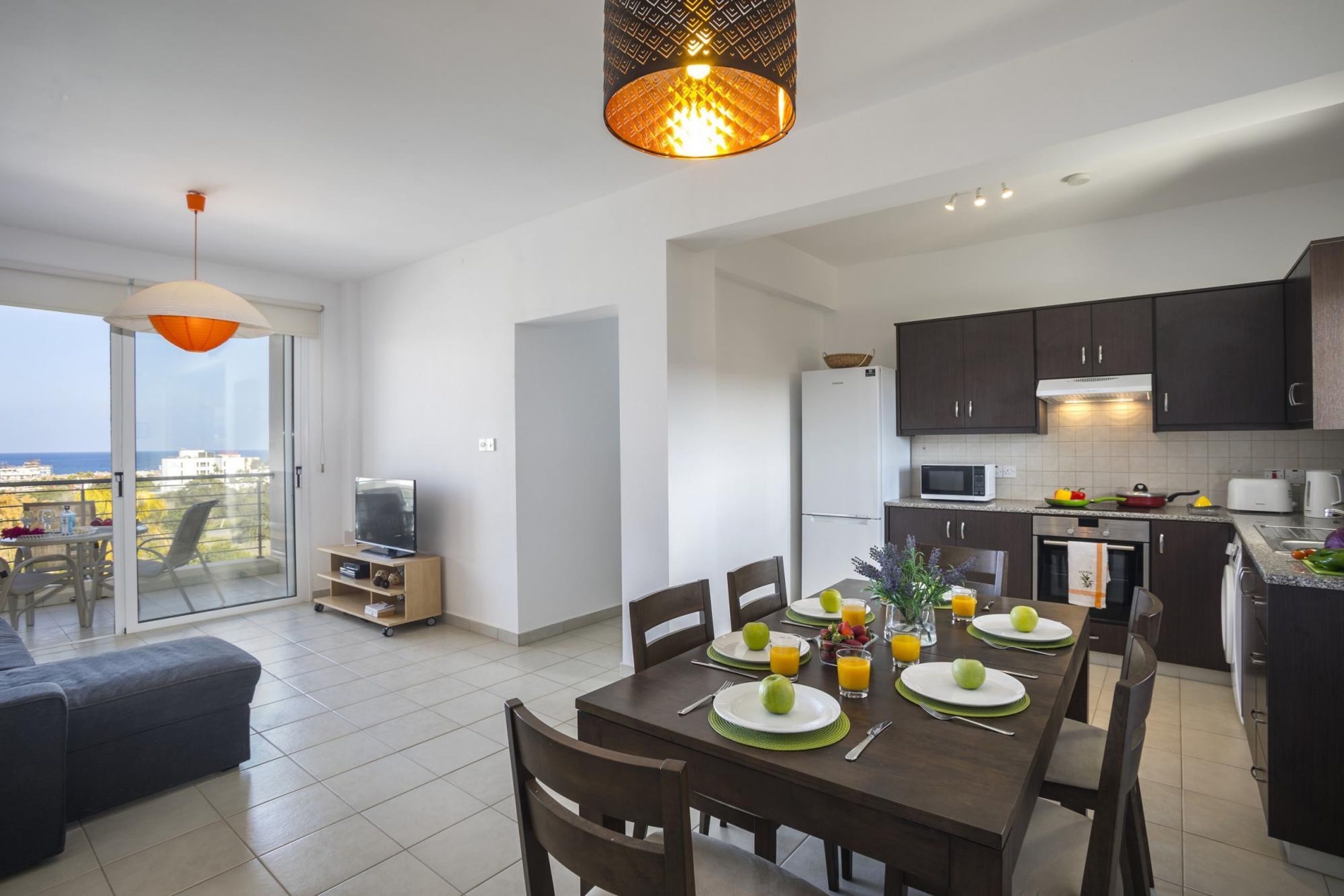 A modern kitchen with dark cabinets, a microwave, and a dining area with a table set for two.