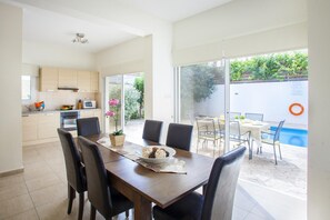 Une cuisine moderne avec un coin repas, une piscine et une vue sur la verdure.