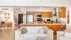 A modern kitchen with wooden cabinets, a central island, and stainless steel appliances. - Protaras Beachfront Villa Pietra (Paralimni)