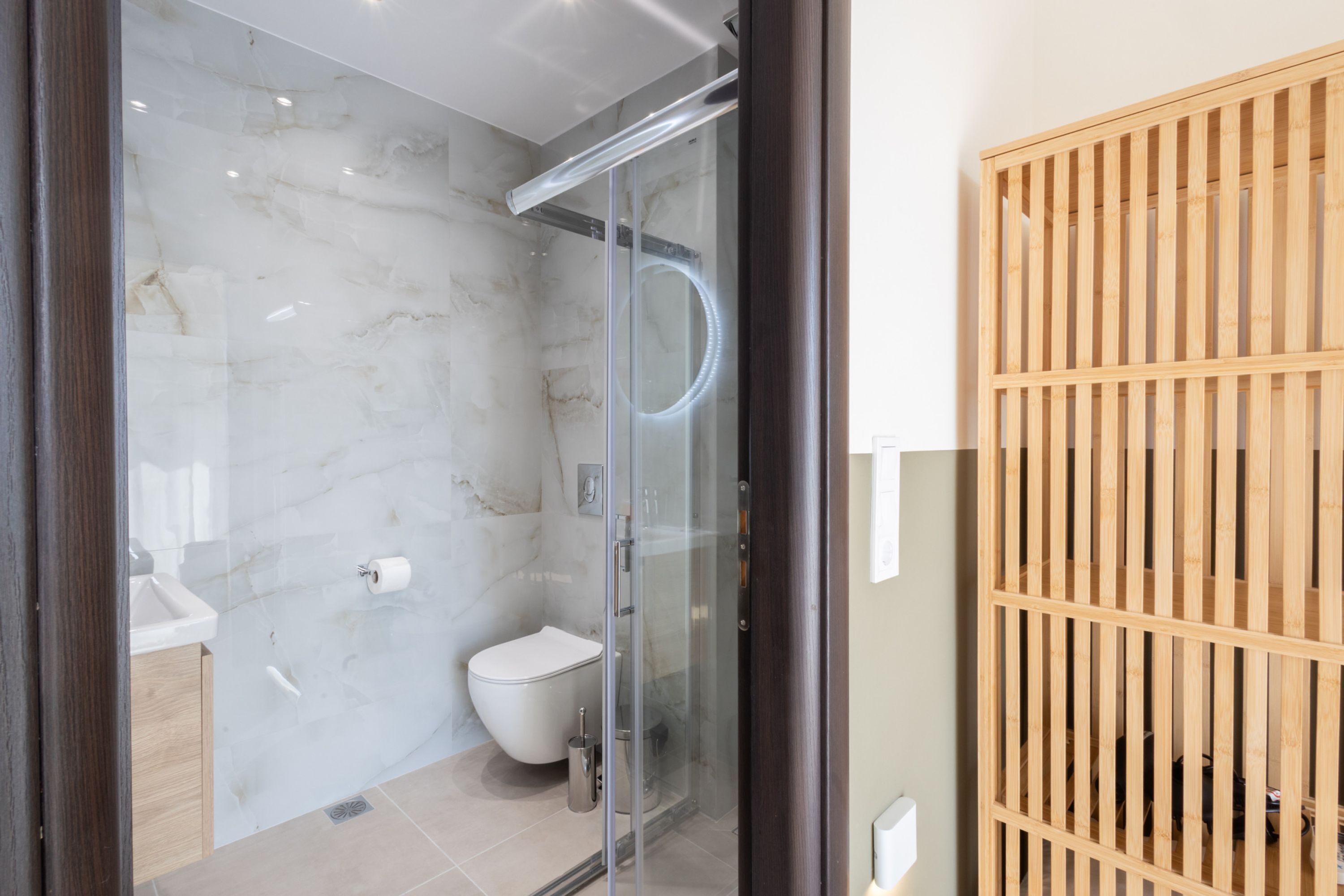 A modern bathroom with a glass-enclosed shower, a toilet, and a sink.