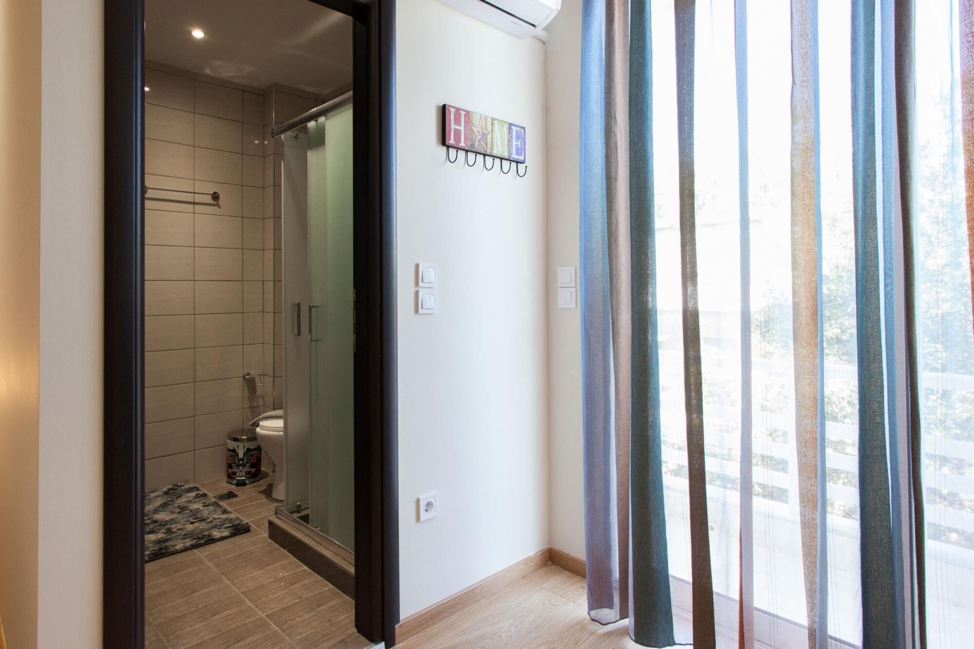 Une salle de bain moderne avec une douche à parois de verre, des toilettes et un petit tapis sur le sol.