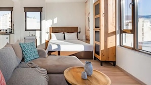 A modern hotel room with a bed, a sofa, a wooden wardrobe, and a small table. - Explore Nightlife Near an Apartment With an Acropolis View (Athens)
