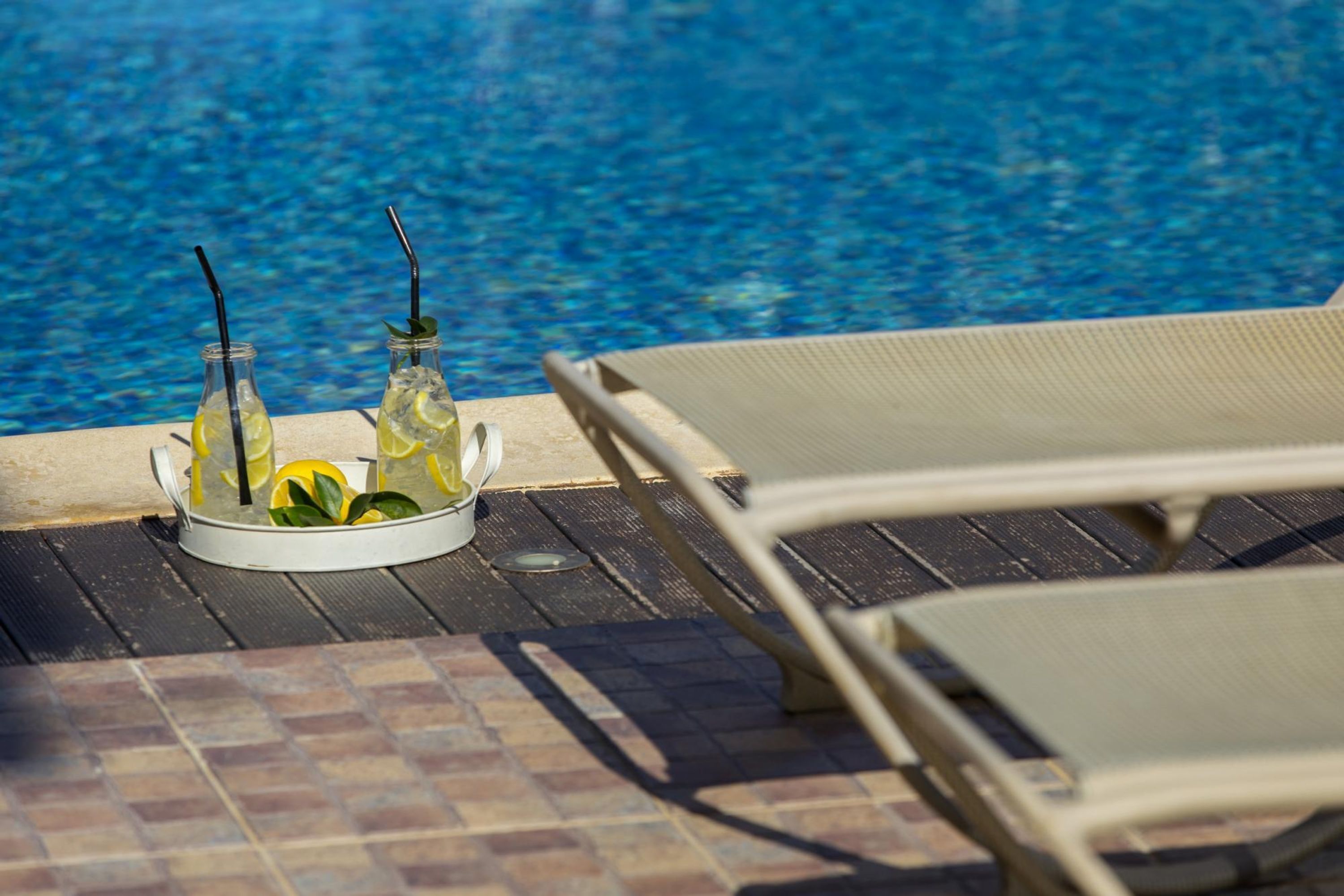 A poolside area with lounge chairs and a tray of drinks.