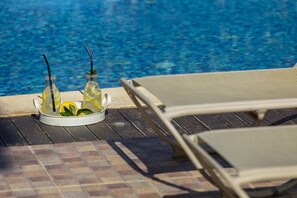 Un espace aménagé au bord de la piscine, avec des chaises longues et un plateau de boissons.