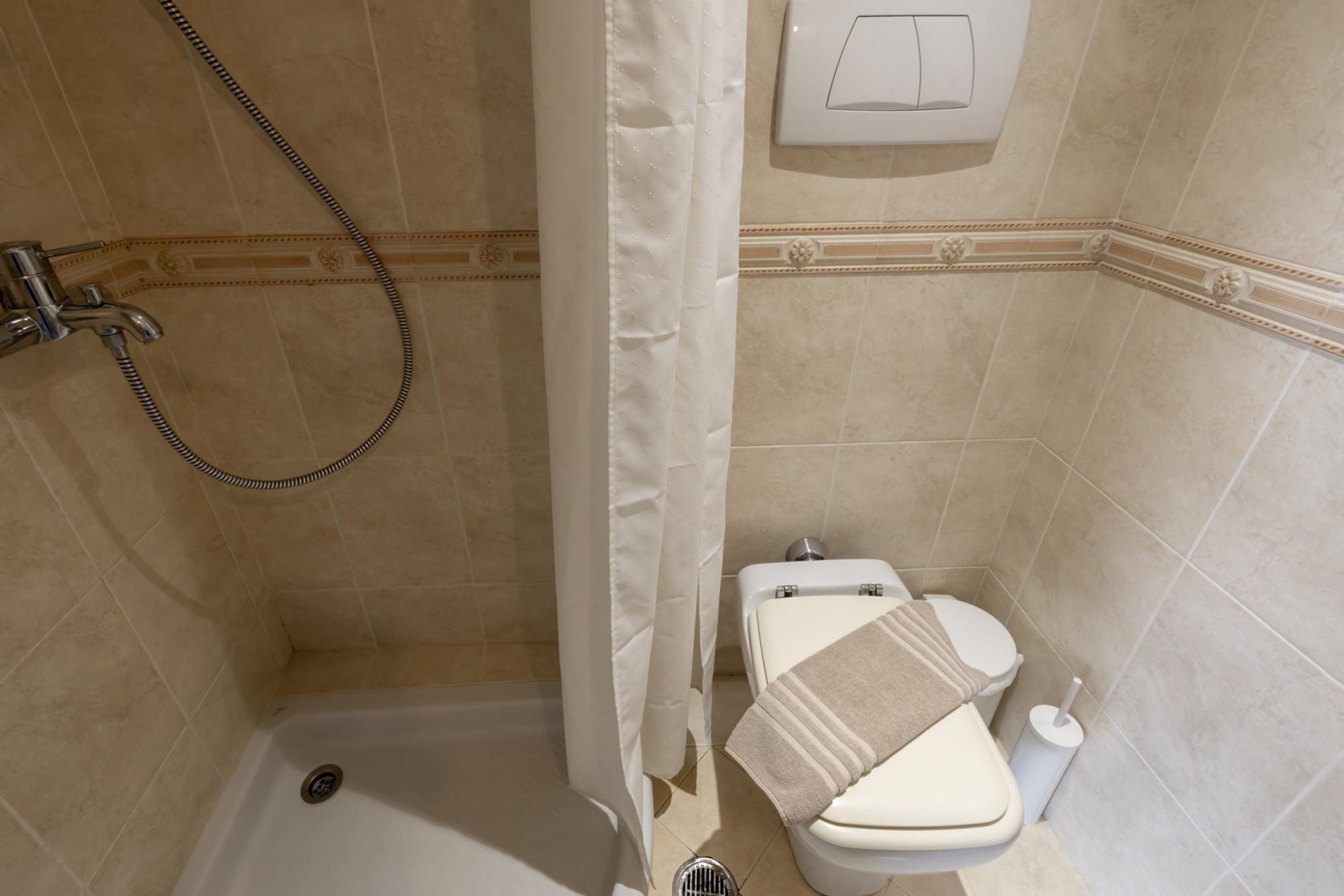A bathroom with a shower, toilet, and a towel rack.